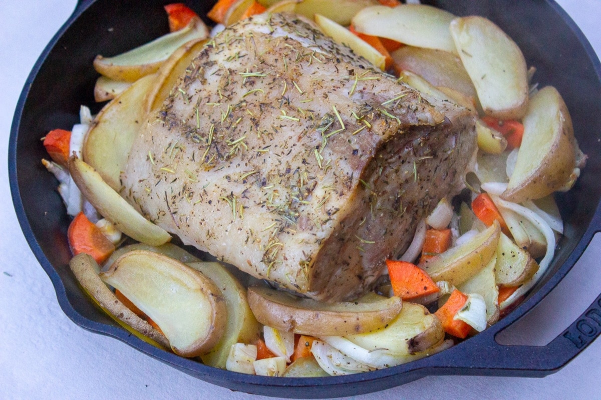 boneless pork roast in pan with veggies partially cooked