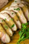 sliced pork roast on cutting board with gravy and potatoes p