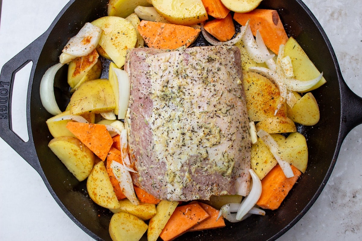 uncooked pork roast with veggies in skillet