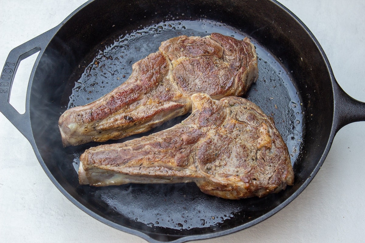 2 veal chops searing in skillet