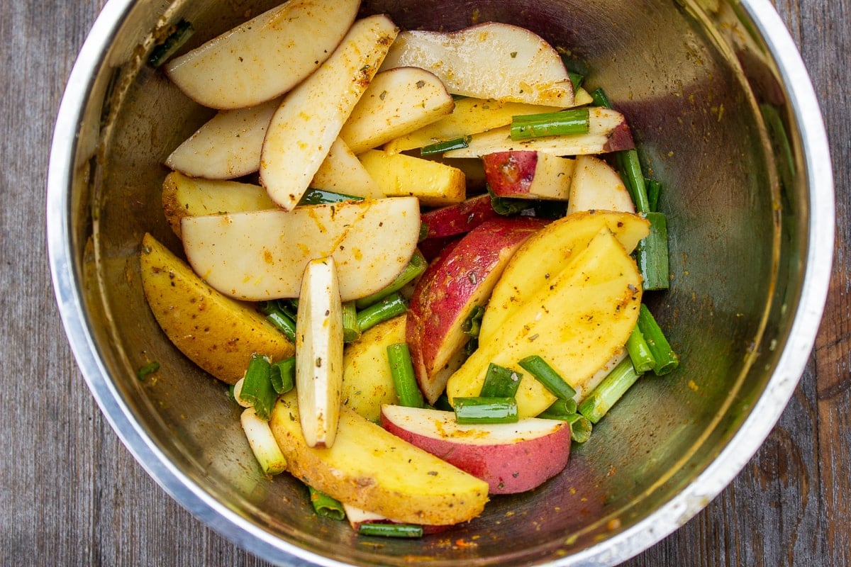 potatoes and onions mixed with seasoning in bowl