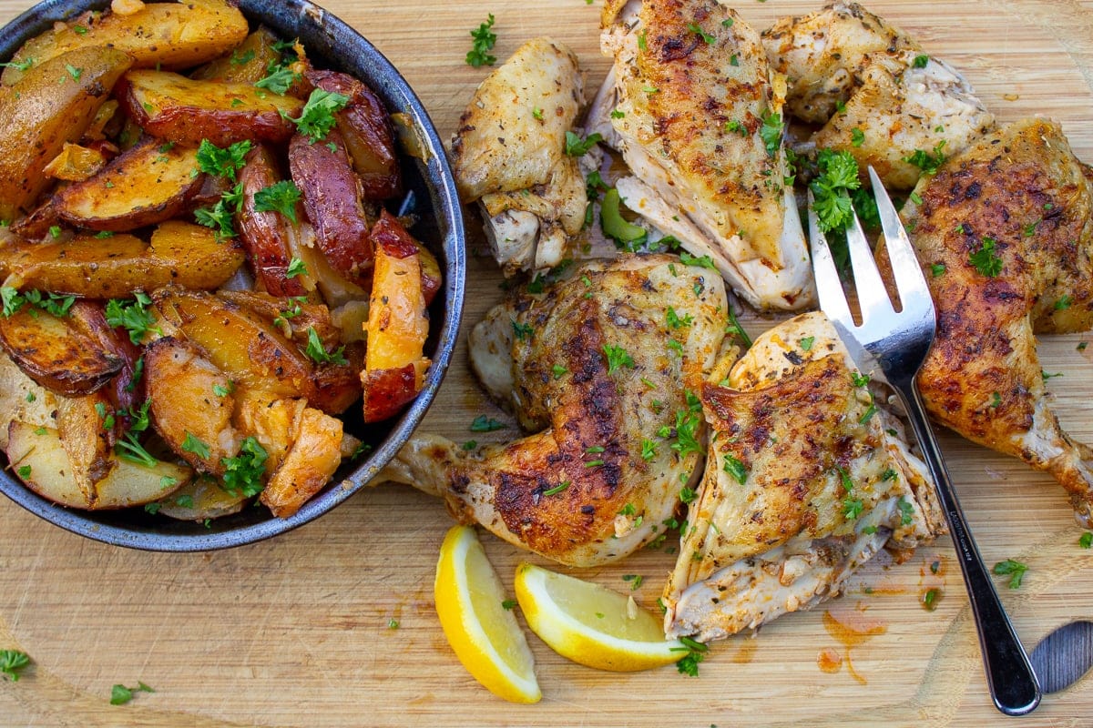 cut up chicken on cutting board with bowl of potatoes