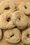 sesame seed bagels piled on cutting board p