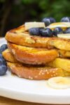 stack of banana French toast on plate with berries and banana slices p