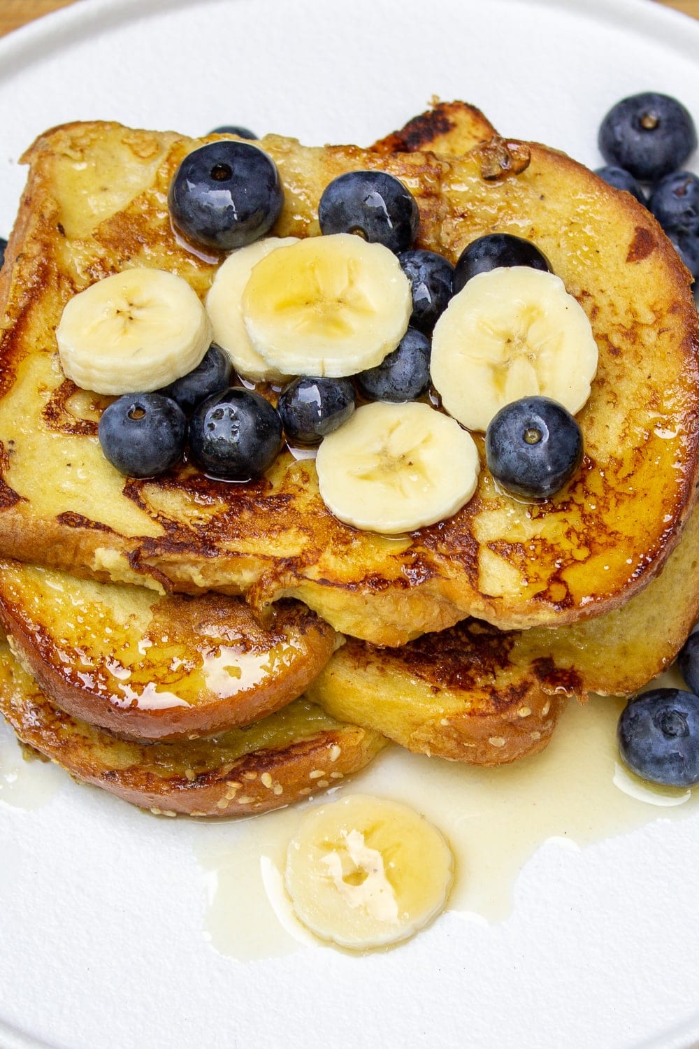 stack of banana French toast on plate with berries and banana slices p1