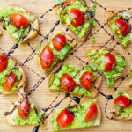avocado crostini pieces on cutting board with drizzle