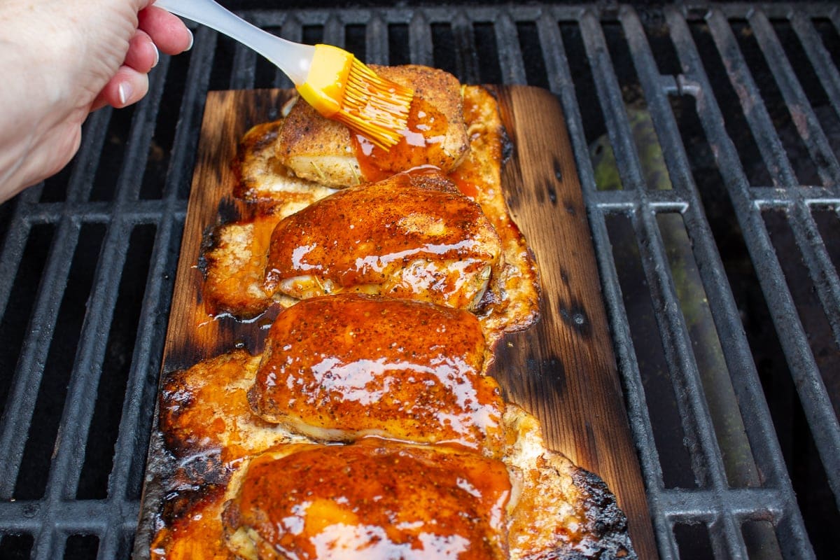 chicken thighs on plank on grill with sauce