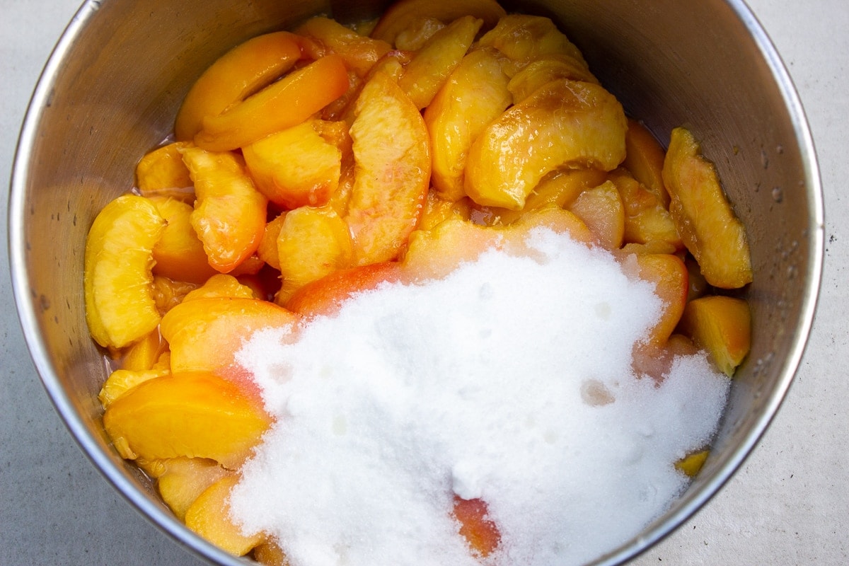 sliced peaches in pot with sugar and lemon