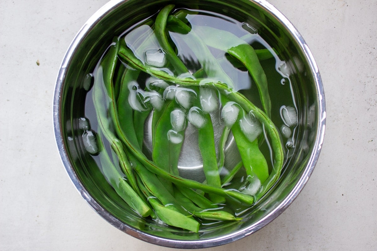microwaved green beans in ice water in bowl
