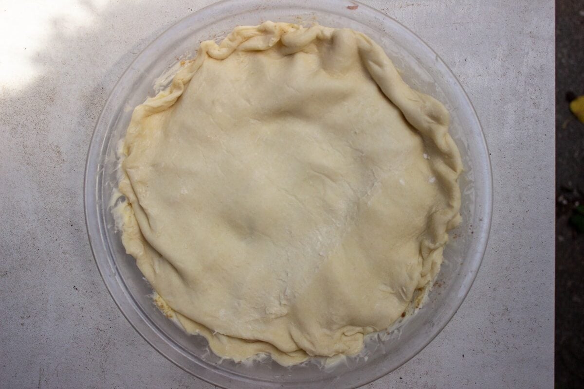 dough covering peaches in pie plate