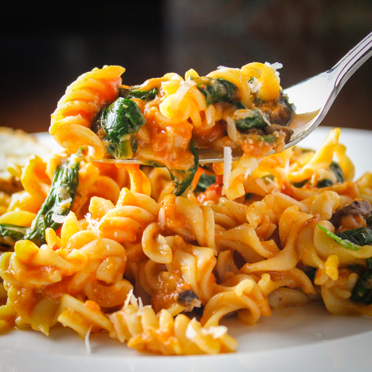 plate of pasta with spinach tomato and cheese