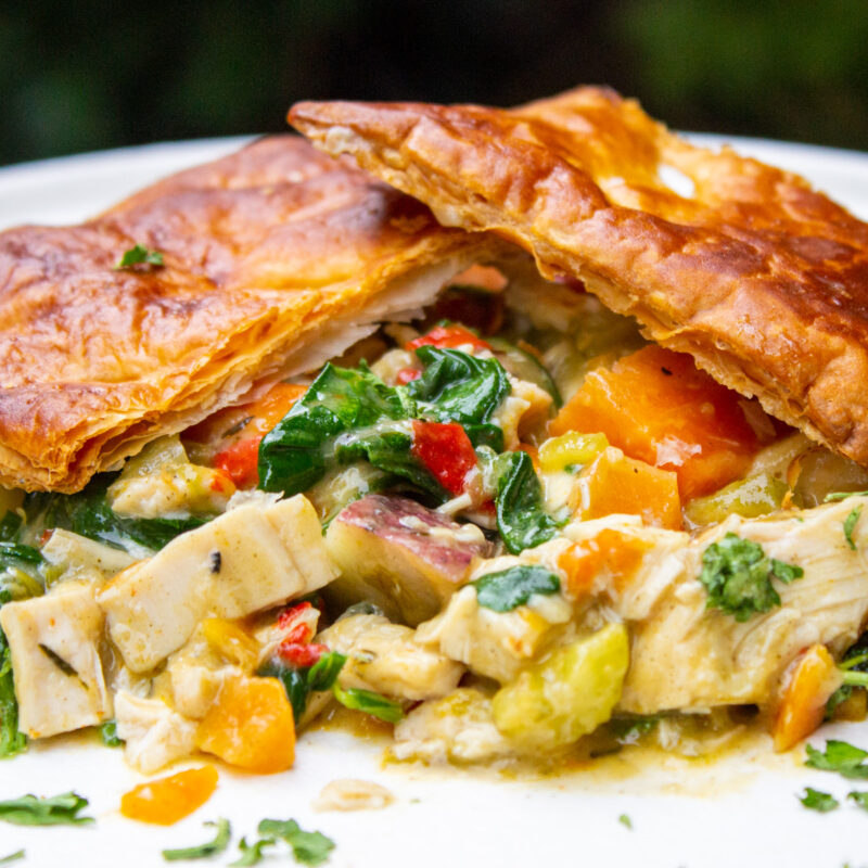 chicken pot pie topped with puff pastry crust on plate