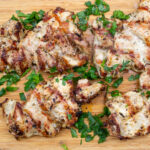 grilled chicken pieces on cutting board