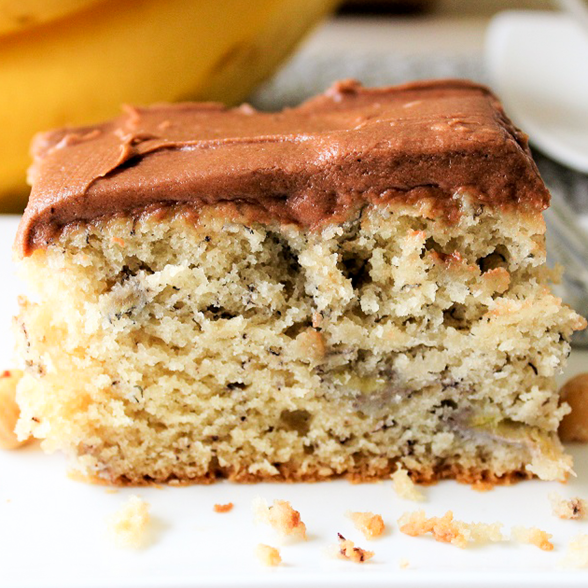 piece of banana cake with chocolate frosting on plate