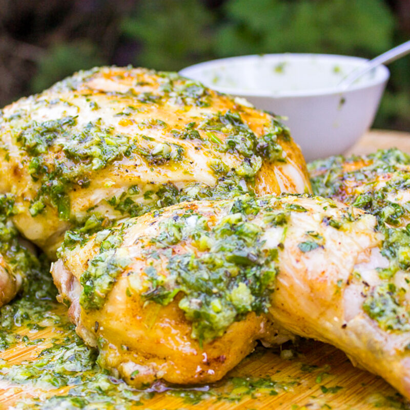 flattened chicken with herb sauce on cutting board