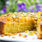 orange polenta cake on a plate with a slice carved out