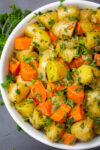 bowl of cooked potatoes and carrots with herbs