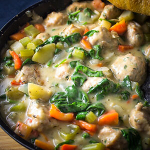 meatball stew in skillet with spinach added