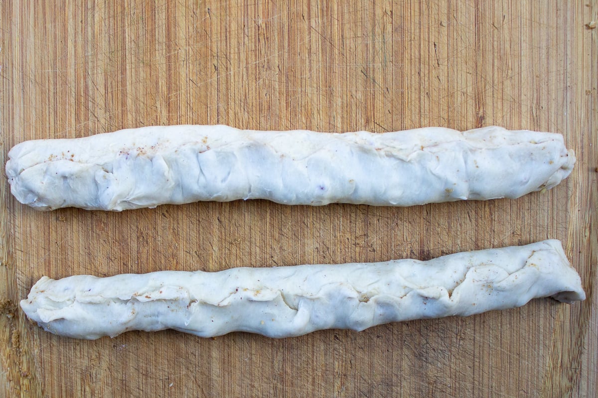 two logs of filled puff pastry on cutting board