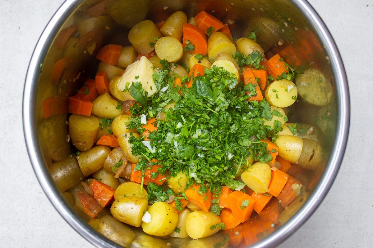 herbs and butter on top of cooked potatoes and carrots in instant pot