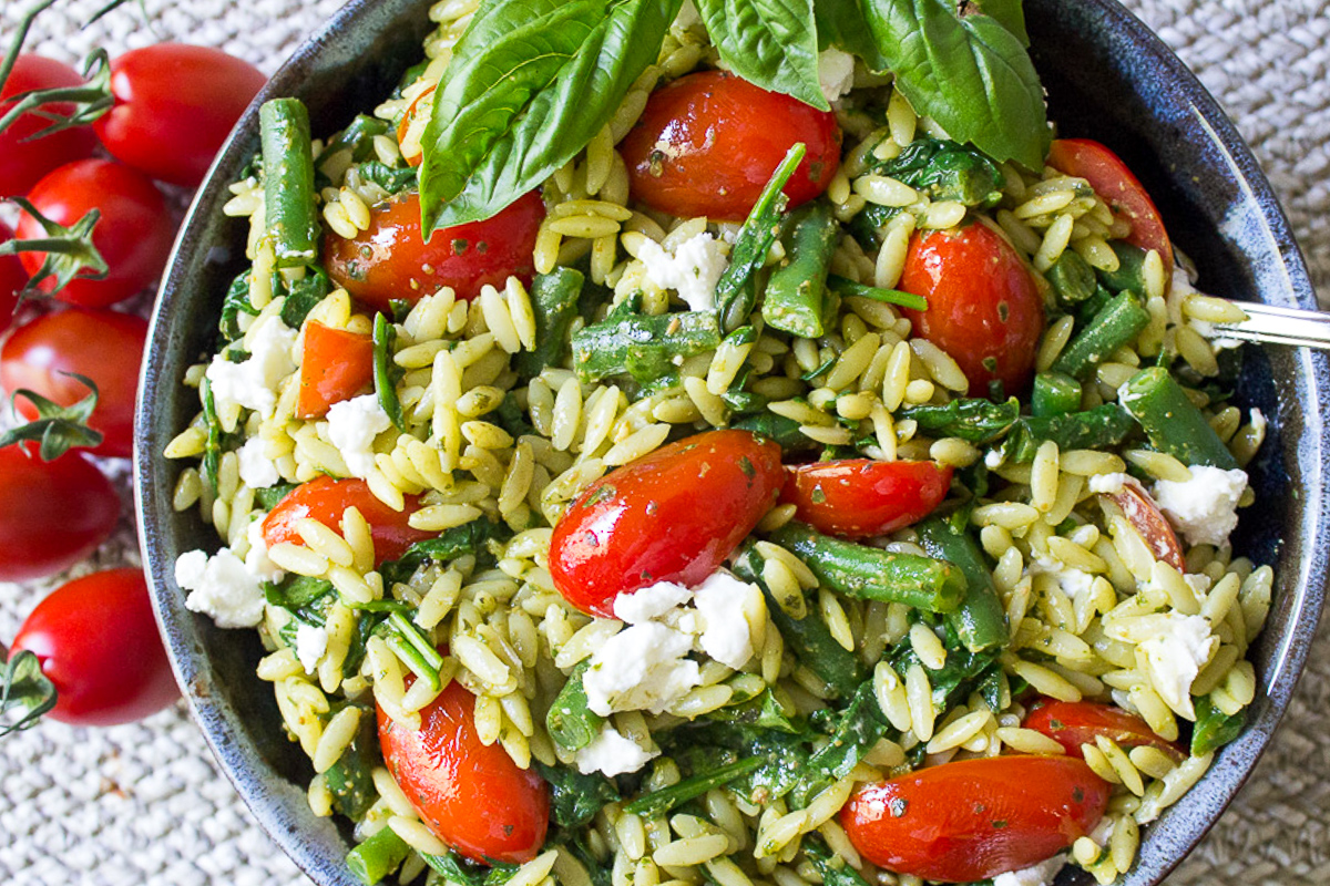 pesto pasta with veggies in bowl with basil