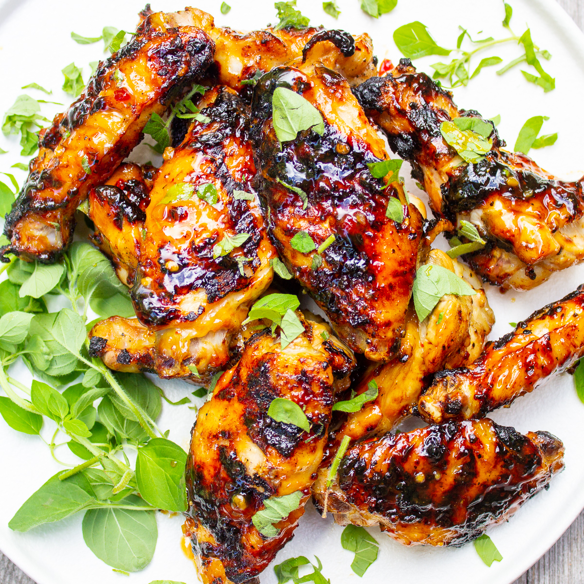pile of grilled wings on plate garnished with fresh oregano