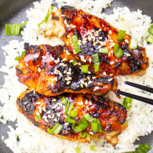 3 chicken wings over rice on plate with chop sticks