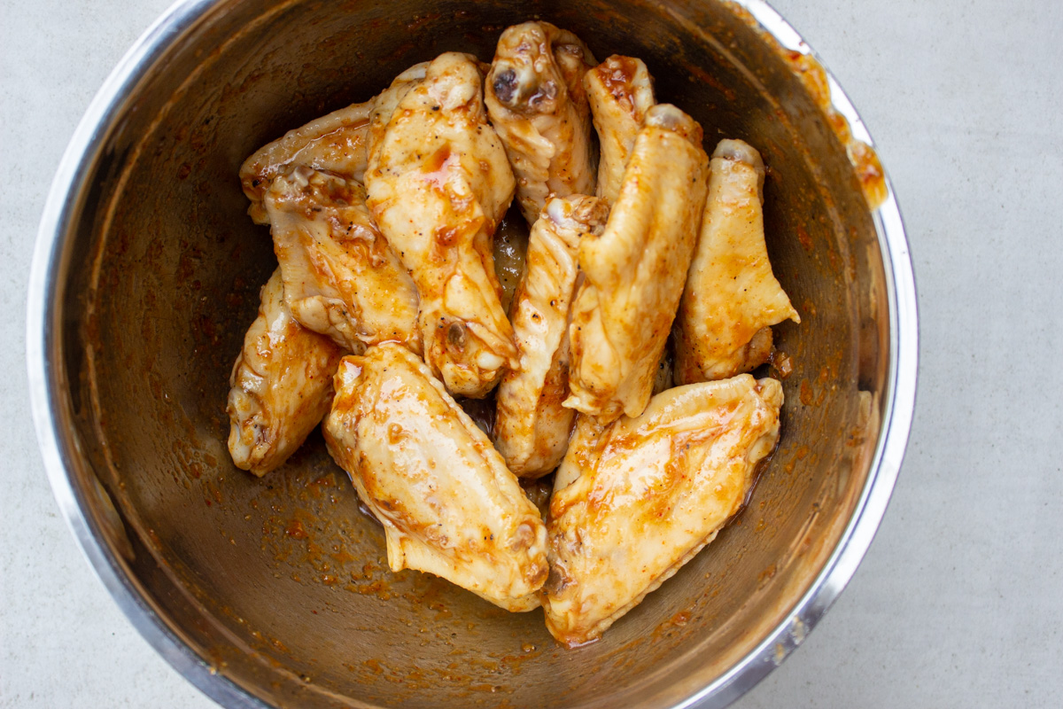 cooked wings in bowl with sauce