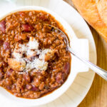 bowl of chili with bread loaf beside it f