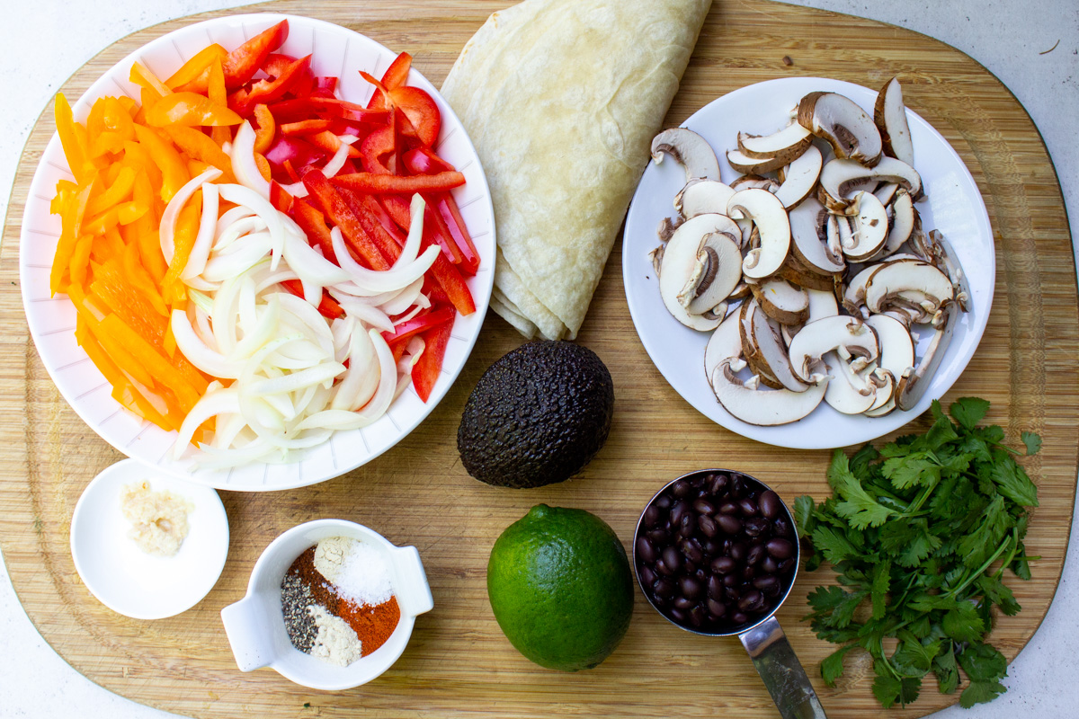 sliced peppers and onions, seasonings, avocado, mushrooms, tortillas, cilantro, beans, lime, garlic