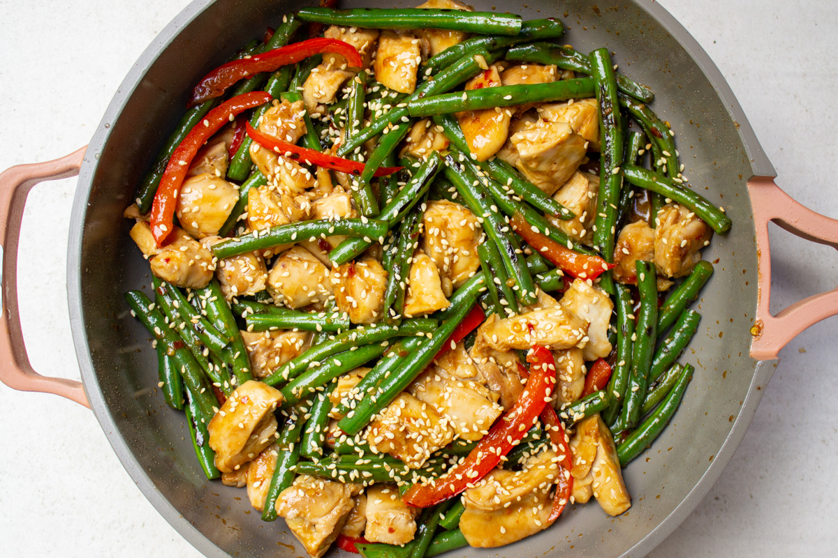 chicken and green bean stir fry in skillet with sesame seeds