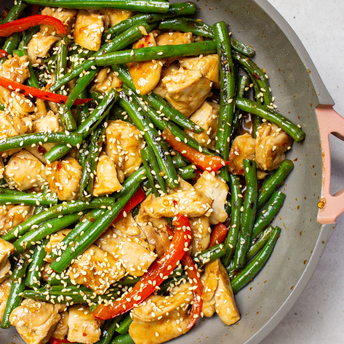 chicken and green bean stir fry in skillet with sesame seeds