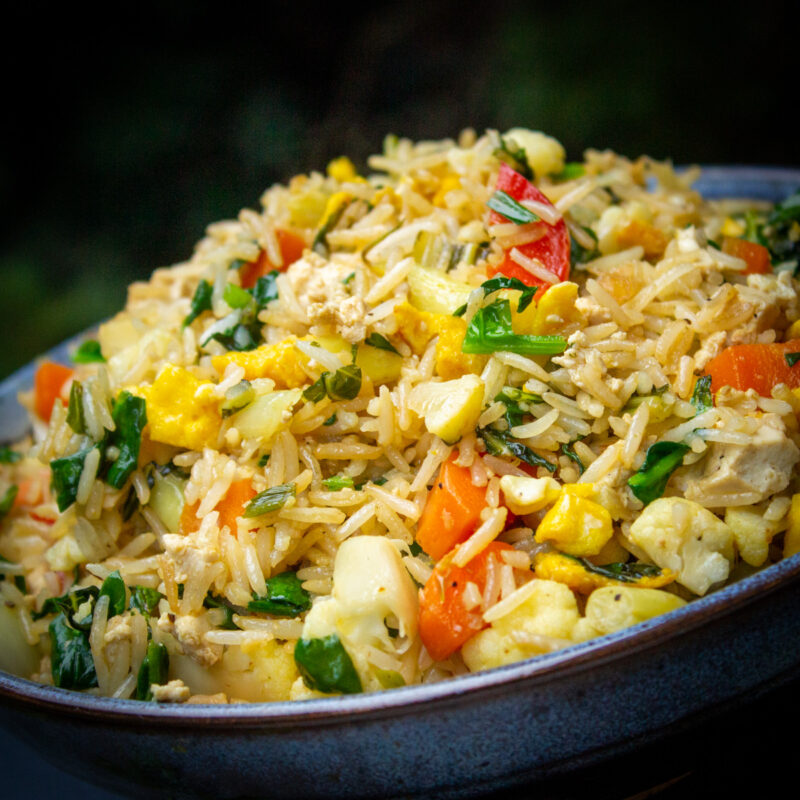 tilted bowl of chinese egg fried rice with vegetables