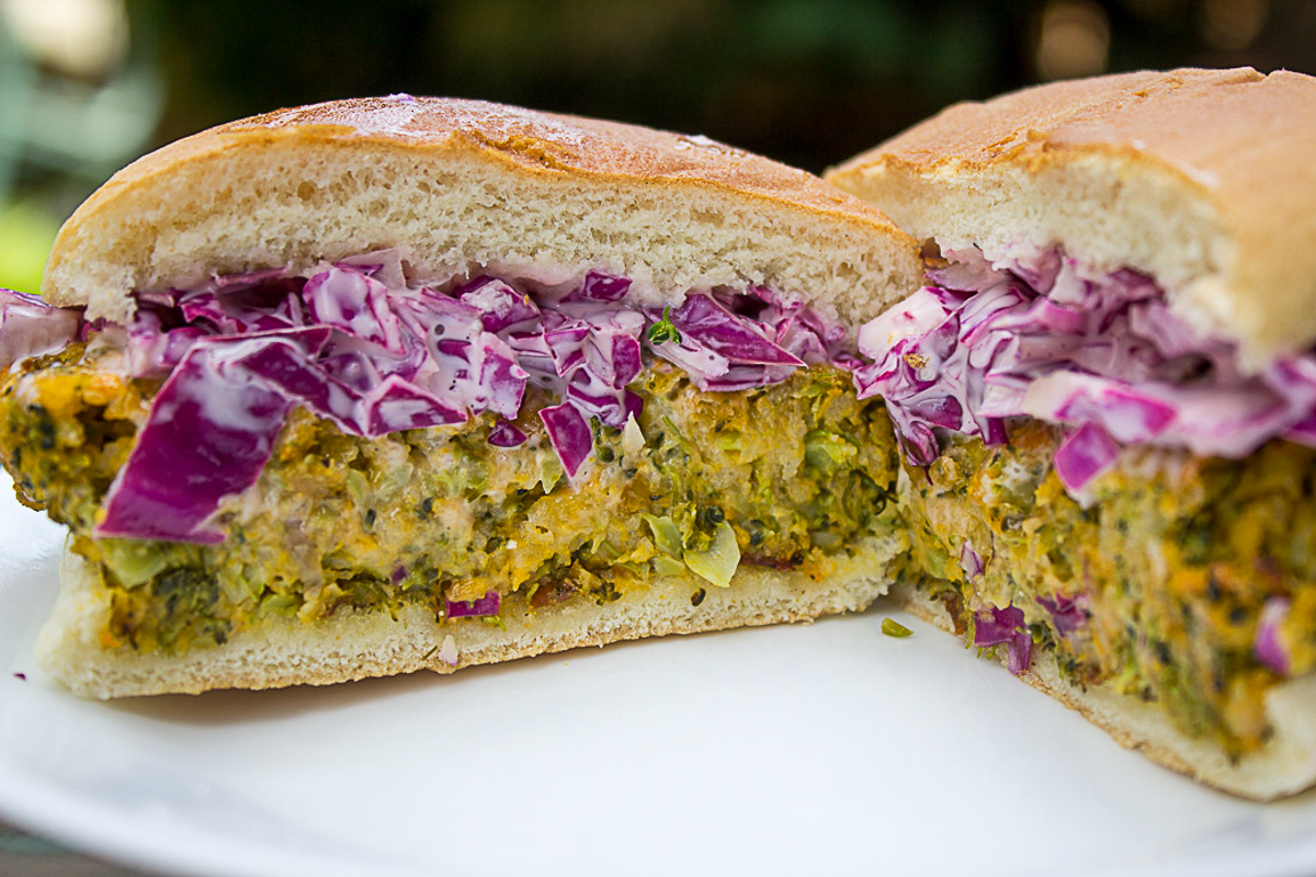 broccoli-burger with purple coleslaw in bun cut in half on plate