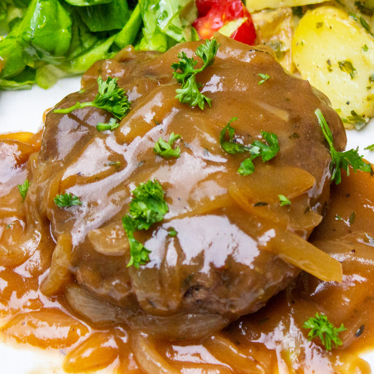 one sous vide hamburger steak on plate with onion gravy