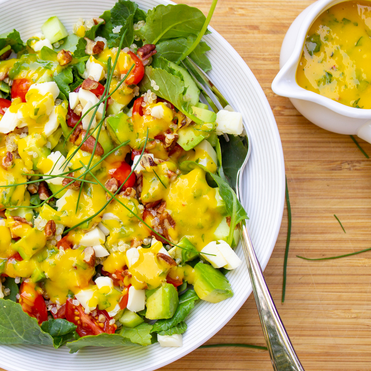 salad with mango dressing and extra dressing in small bowl at the side