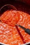 ladle scooping san marzano tomato sauce from pot
