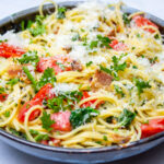 spaghetti carbonara with tomatoes and spinach in bowl
