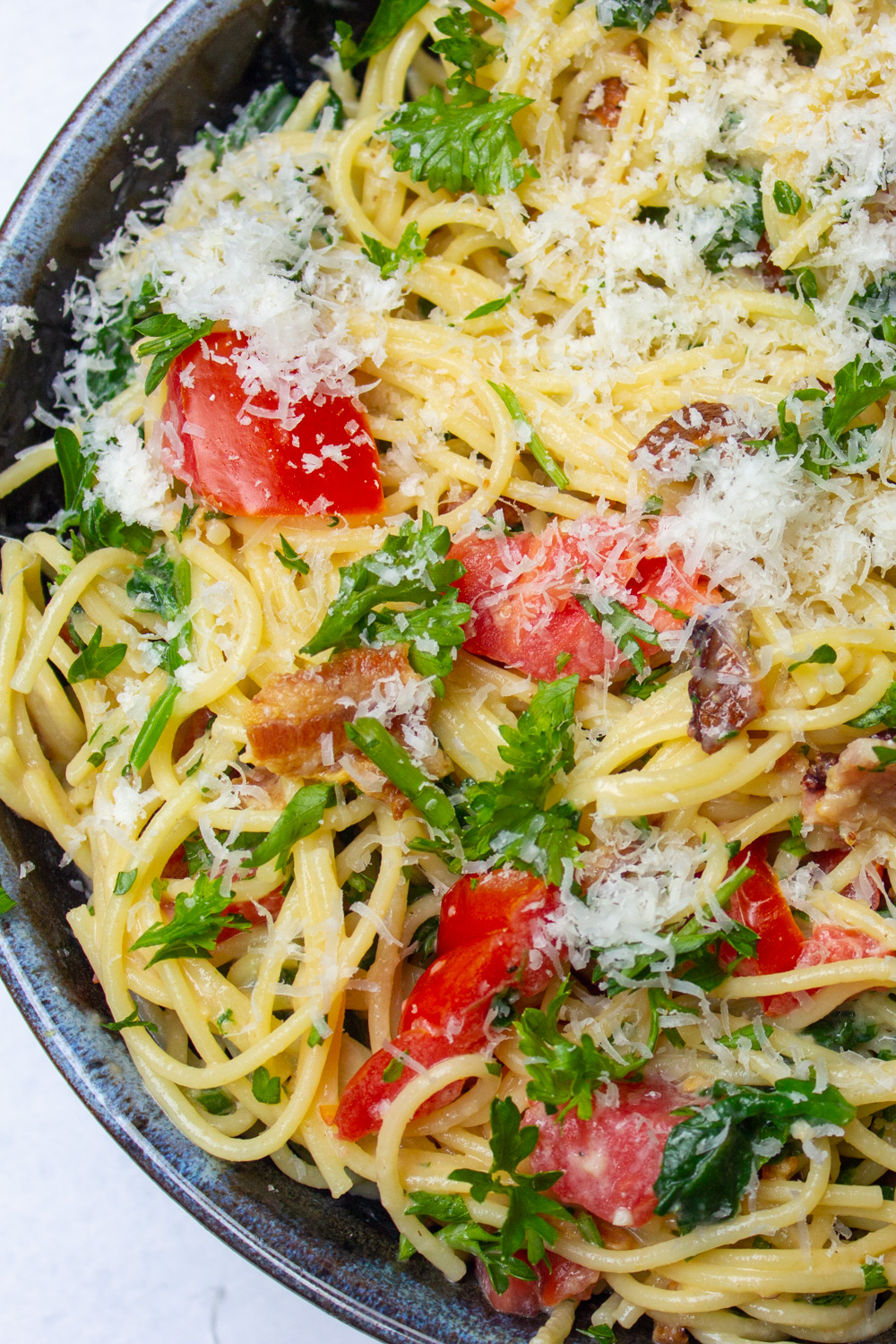 spaghetti carbonara with tomatoes and spinach in a bowl