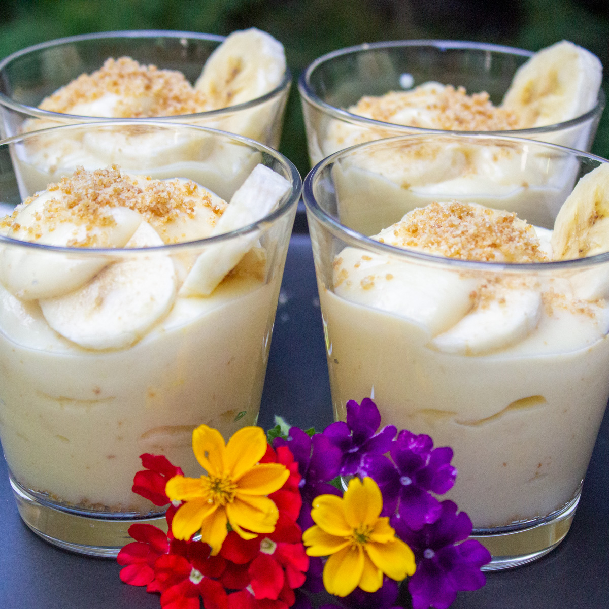 4 banana pudding cups with baby flowers in front of cups