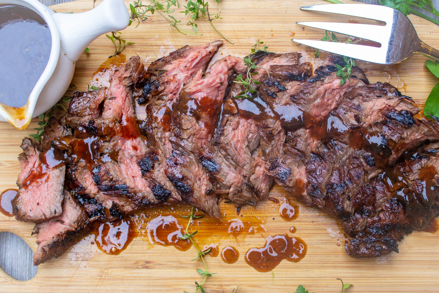 sliced flank steak drizzled with sauce and sauce in cup on side 1