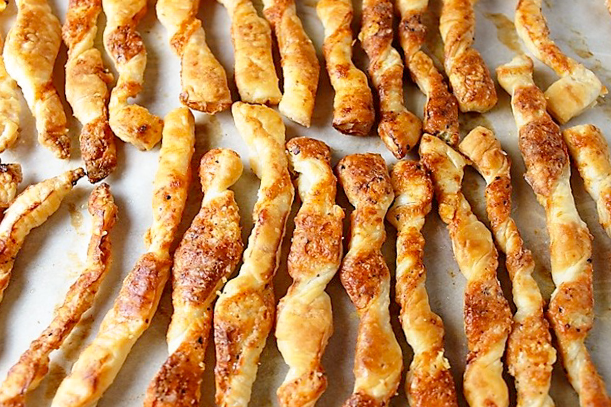 puff pastry cheese twists lying on pan