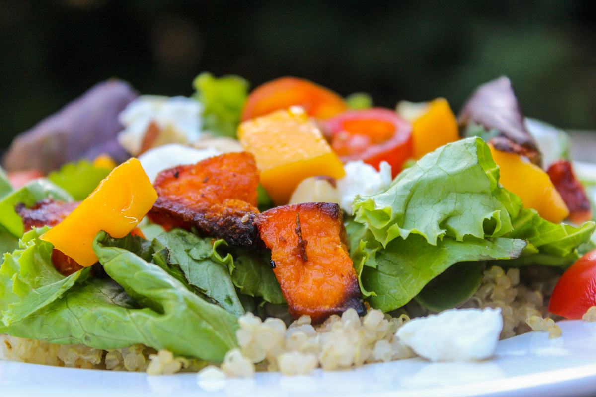close up of salad with quinoa sweet potato nuts and cheese plate