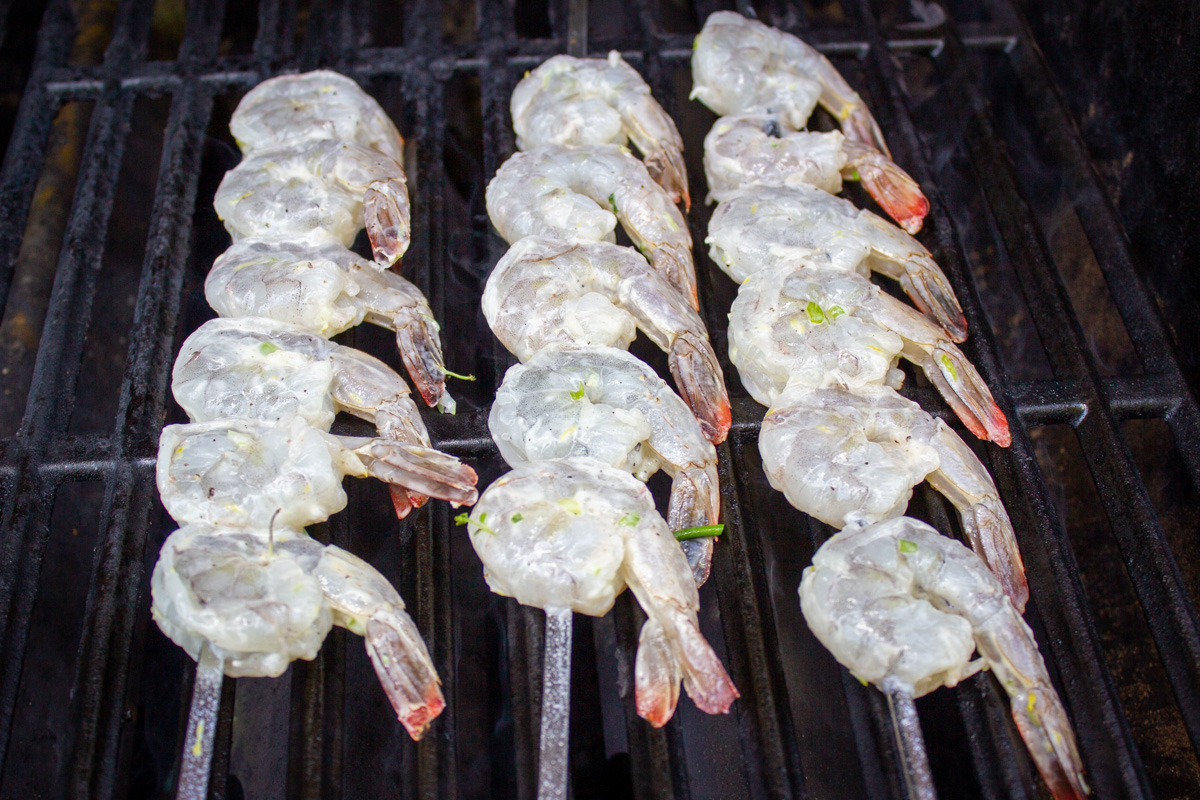 3 skewers of raw shrimp on bbq grates