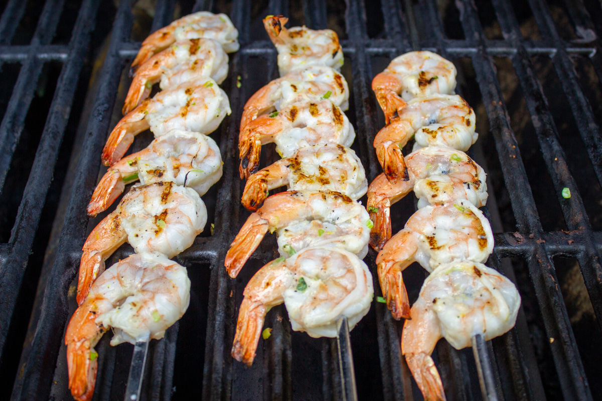 3 skewers of shrimp on bbq grates now cooked