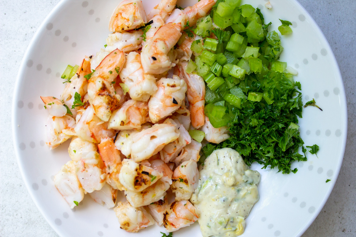 chopped shrimp, celery, mayo dressing, parsley in white bowl