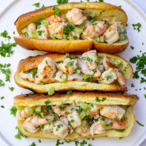 3 shrimp salad rolls on white plate sprinkled with parsley
