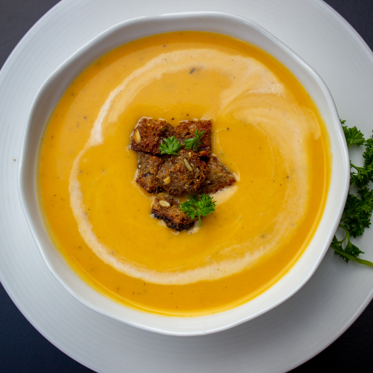 squash apple soup in white bowl with croutons