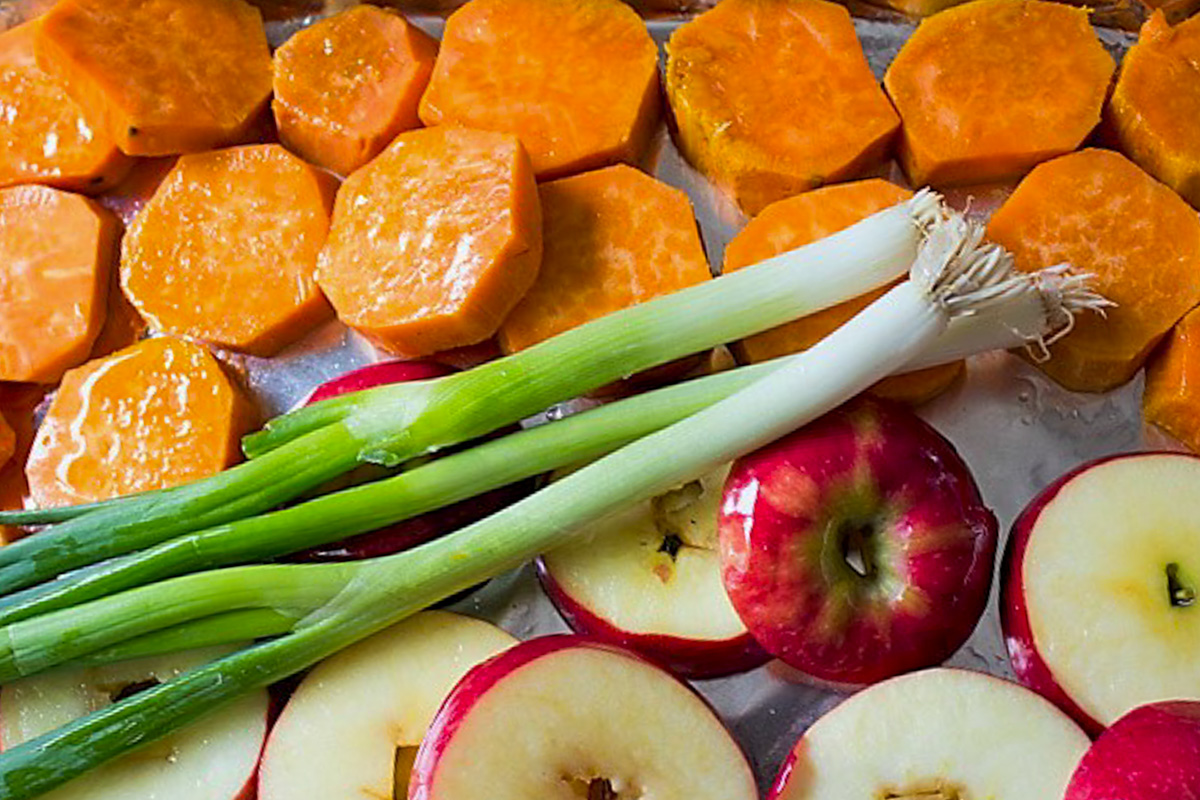 slices of sweet potato and apples and green onions on pan