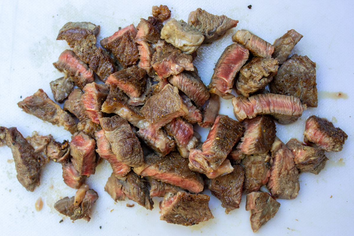 pan seared beef cut into small pieces on cutting board